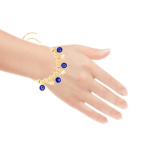A hand displays the Blue Evil Eyes Tiny Elephant Charm Bracelet, featuring a 14k gold-filled chain adorned with blue evil eye charms and a tiny elephant. This adjustable bracelet hangs gracefully around the wrist against a plain white background.